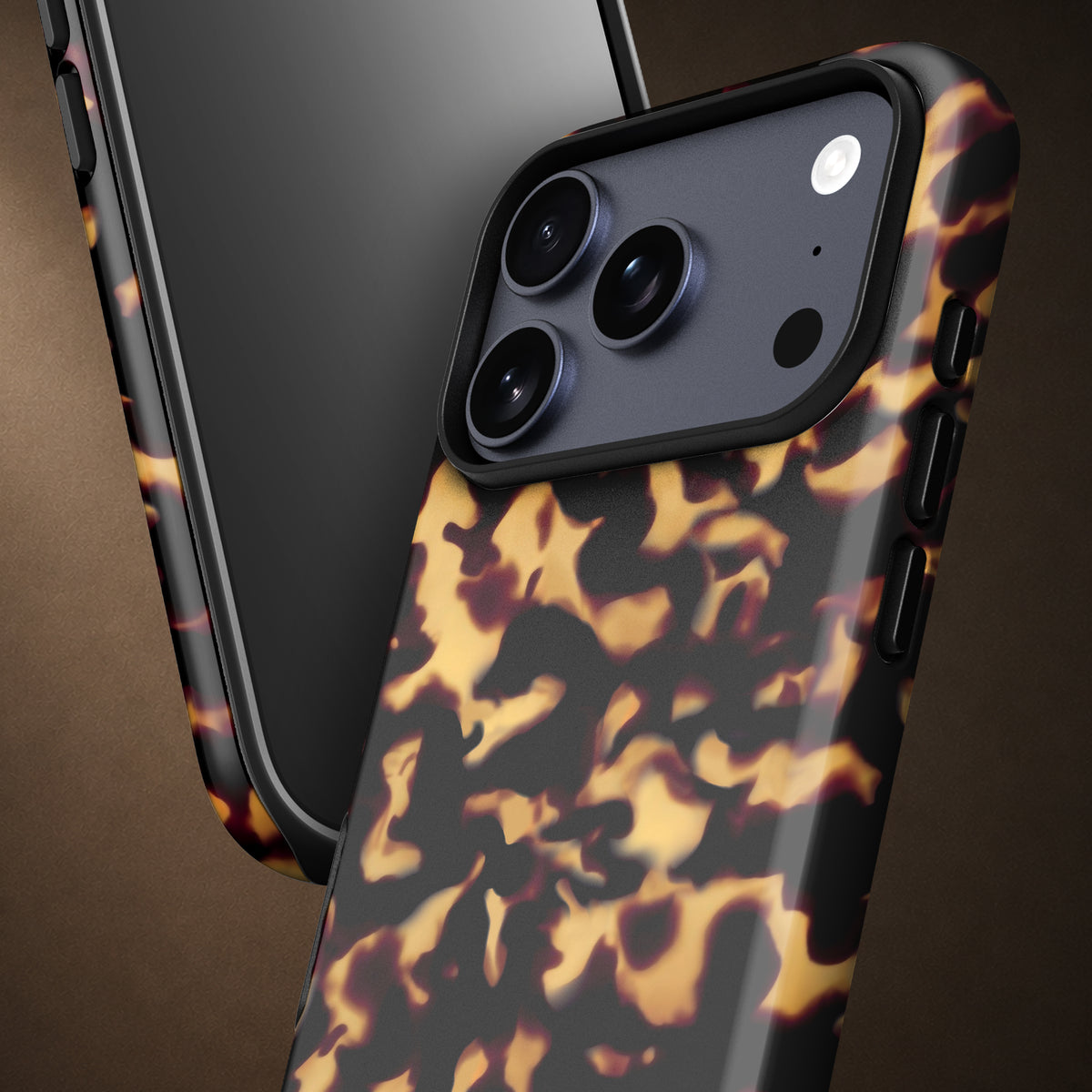 A close-up of a smartphone case with a glossy black and amber-brown tortoiseshell pattern, shown on a phone against a dark brown background.
