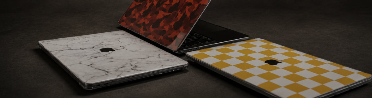 Three Apple MacBooks with custom cases