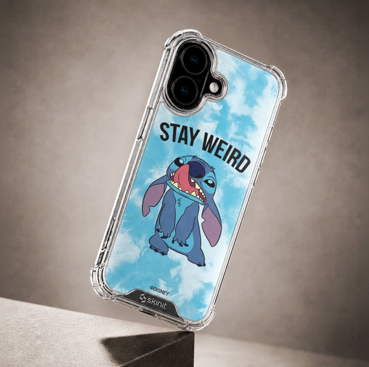 A clear protective phone case with a blue sky and cloud print, featuring the character Stitch and the text 'STAY WEIRD'. The case is shown on a smartphone, resting on a dark gray surface against a textured gray background.